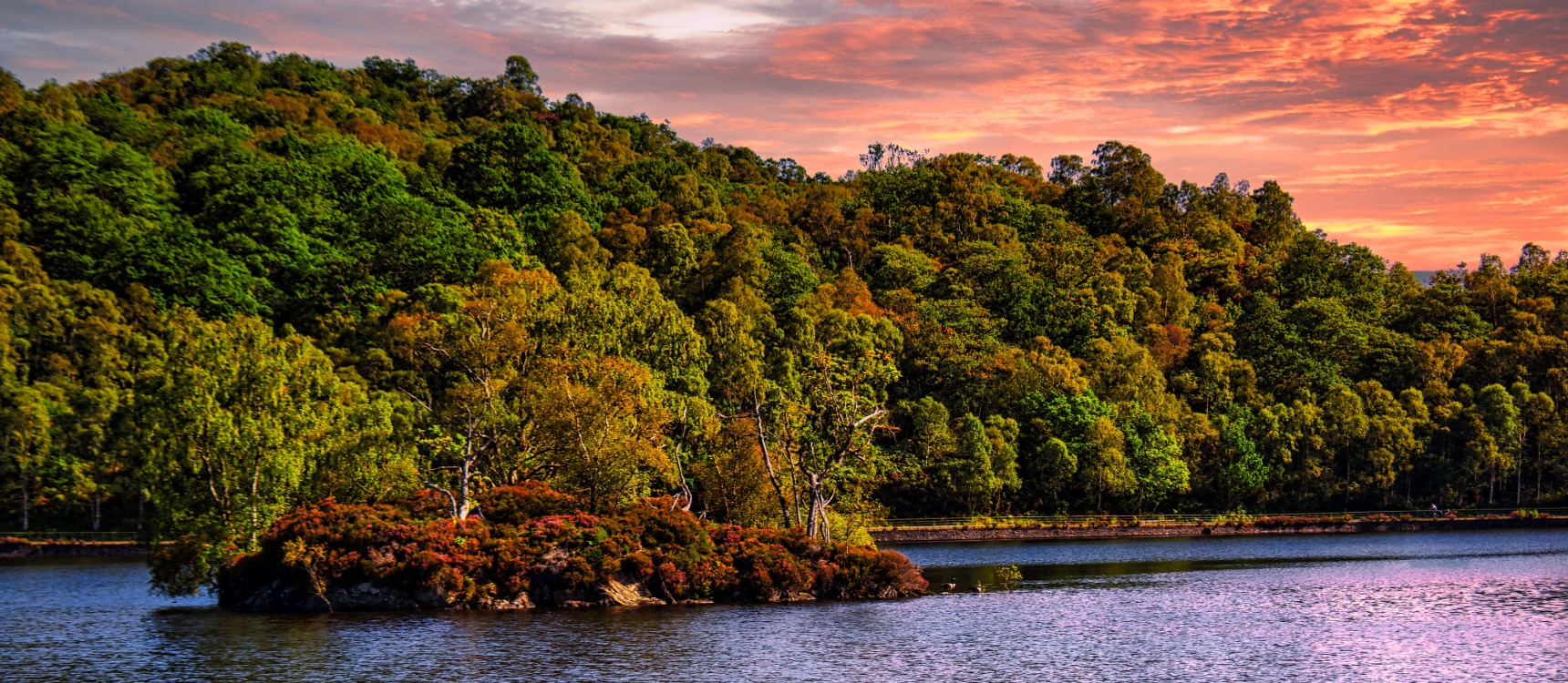 A misty dawn over Loch Katrine with warm golden tones.